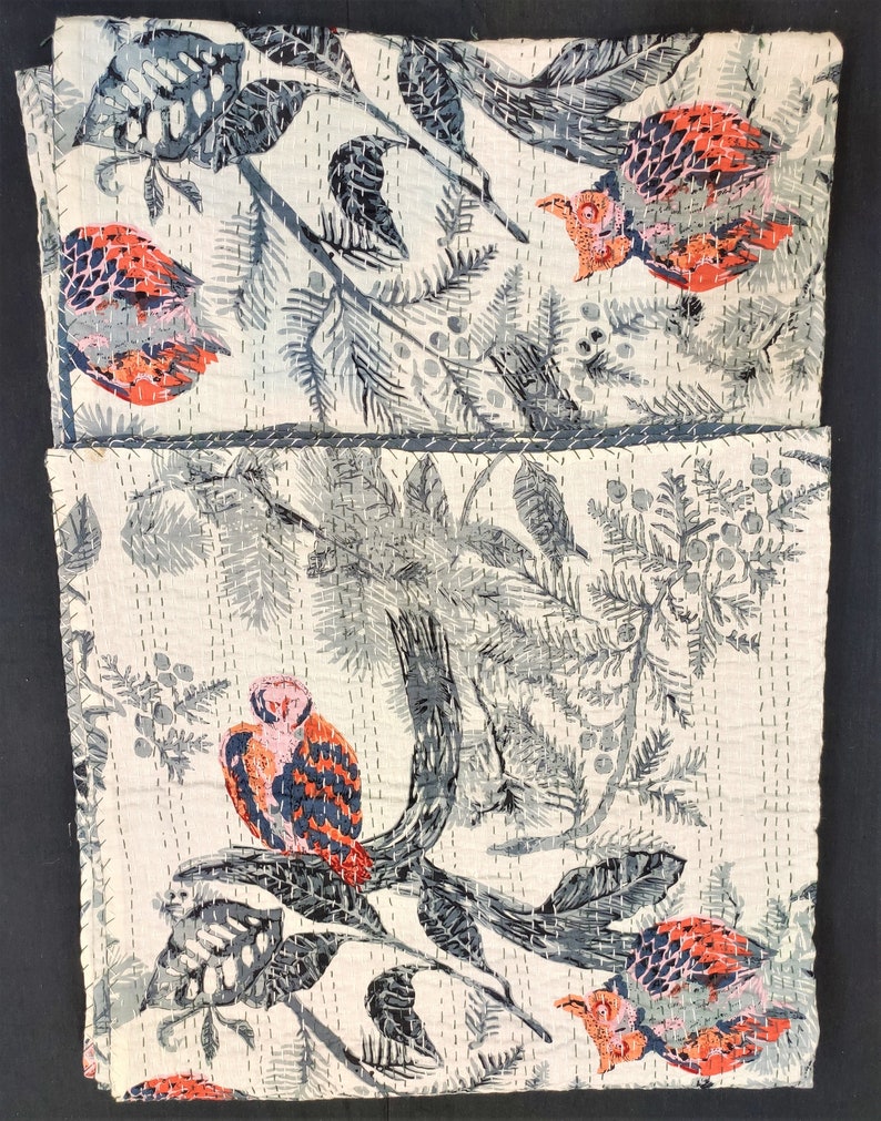May include: A white cotton fabric with a repeating pattern of gray and red birds, leaves, and branches. The fabric is quilted with white thread.
