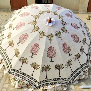 May include: A white cotton patio umbrella with a black and green border. The umbrella features a repeating pattern of pink and green trees.