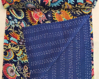 May include: A folded quilt featuring a dark blue base with a vibrant floral pattern in shades of pink, yellow, orange, and light blue. The reverse side is a solid dark blue fabric with white running stitch details throughout the entire surface.