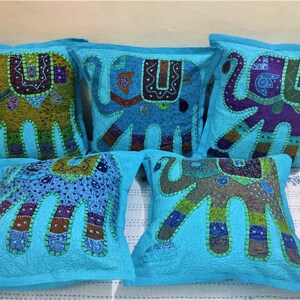 May include: Five turquoise blue cushion covers with embroidered elephant designs. Each cushion cover features a different colour elephant with intricate details and patchwork fabric.