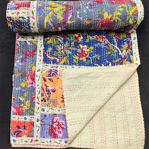 May include: A patchwork quilt with a floral print in shades of blue, pink, orange, and green. The quilt is made of cotton and has a white backing. It is hand-stitched and has a traditional kantha design.