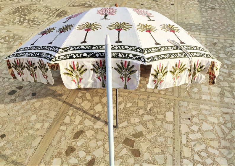 May include: White cotton patio umbrella with a green and pink floral print. The umbrella is open and the pole is white.