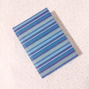 May include: A blue and green striped notebook with a white background. The notebook has a textured cover.