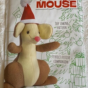 May include: A sewing pattern for a Monty Mouse plush toy, wearing a red and white Santa hat. The design includes a Christmas tree and the text "Toy Sewing Pattern" and "Great Stocking Filler!"