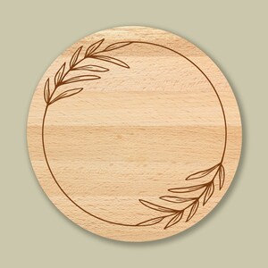 K&ouml;nnte beinhalten: Ein rundes, h&ouml;lzernes Schneidebrett mit einem dekorativen, in den Rand geschnitzten Blumendesign. Das Brett ist aus hellem Holz und hat eine nat&uuml;rliche Maserung.