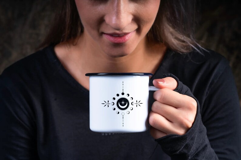 May include: A white enamel mug with a black and white moon phase design. The mug has a black rim and handle.