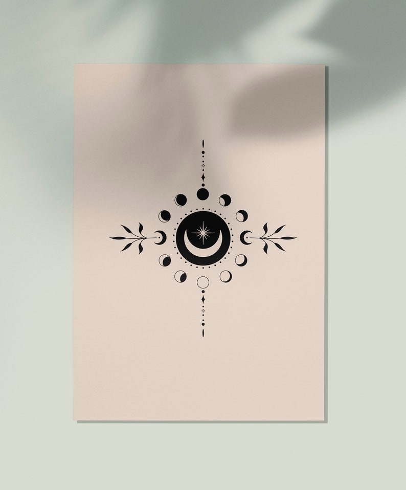 May include: A black and white illustration of a crescent moon with a star inside, surrounded by a circle of smaller moons in various phases. The design is centered on a light pink background.