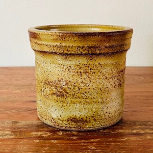 Könnte beinhalten: Ein gelber Keramik-Besteckhalter mit braunen Flecken und einem braunen Rand.