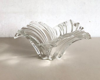 Könnte beinhalten: Eine klare Glasschale mit einem wellenförmigen, organischen Design. Die Schale ist wie eine Blume mit mehreren Blütenblättern geformt.