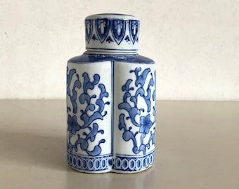 Może przedstawiać: Biały ceramiczny dzbanek z niebiesko-białym wzorem kwiatowym. Dzbanek ma pokrywkę i jest ozdobiony powtarzającym się wzorem kwiatów i liści.
