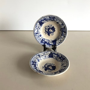 Puede incluir: Dos cuencos de cerámica azul y blanco con un diseño floral y de dragón. Los cuencos están apilados uno encima del otro.