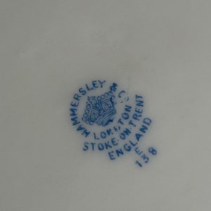Może przedstawiać: Niebieska i biała pieczątka na białym tle. Pieczątka zawiera napis "Hammersley, Stoke-on-Trent, Anglia 1838" i przedstawia koronę.