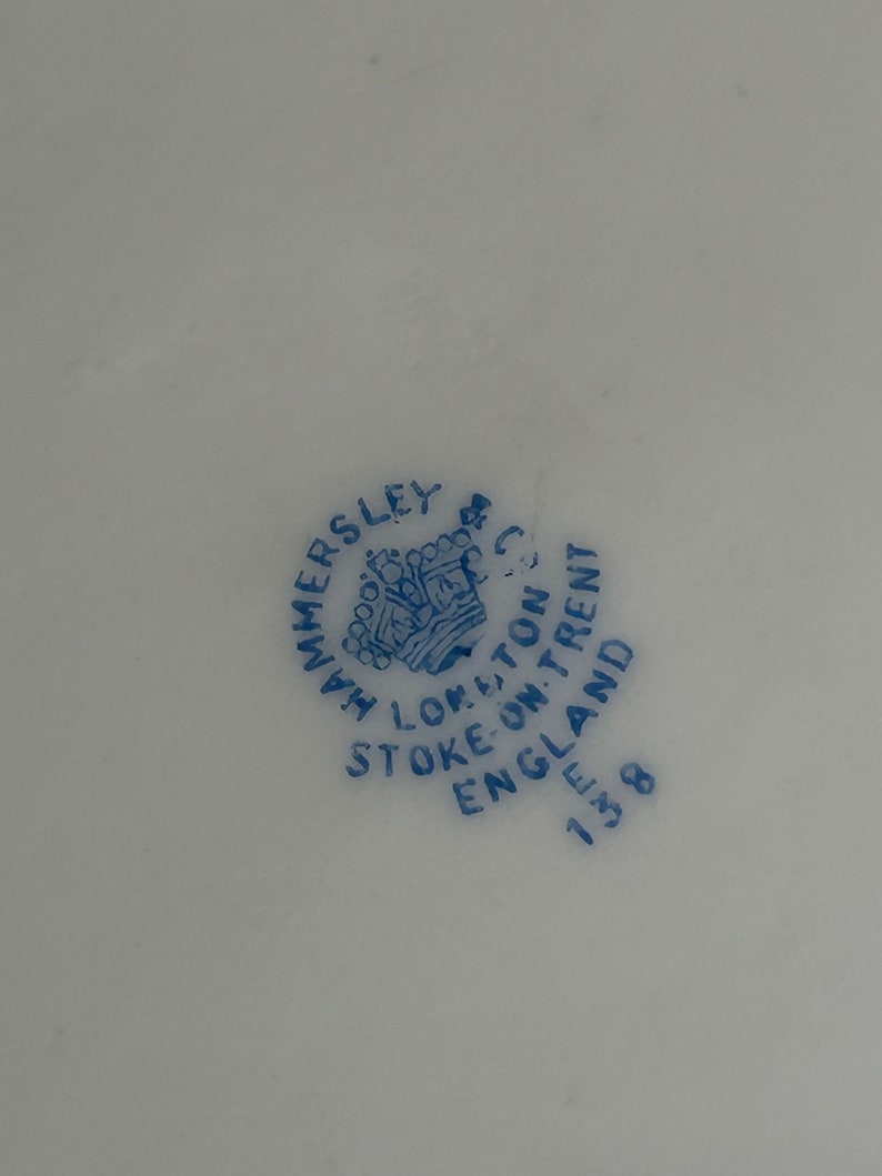 Może przedstawiać: Niebieska i biała pieczątka na białym tle. Pieczątka zawiera napis "Hammersley, Stoke-on-Trent, Anglia 1838" i przedstawia koronę.