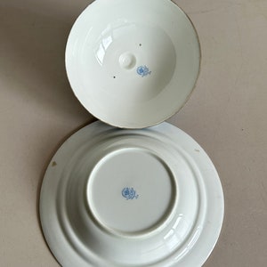 Może przedstawiać: Sp&oacute;d dw&oacute;ch białych ceramicznych misek z niebieskim wzorem kwiatowym. Obie miski są okrągłe i mają niewielki rant wok&oacute;ł krawędzi.