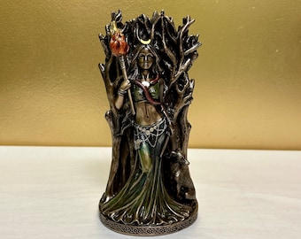 May include: A bronze statue of a woman standing in a forest. She is holding a torch in one hand and a crescent moon in the other. A wolf is sitting at her feet. The statue is on a base with a Celtic knot design.