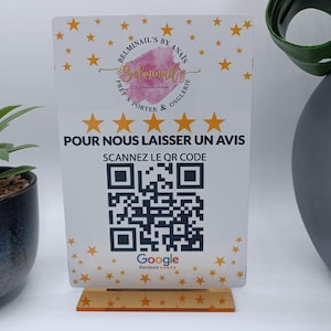 Peut inclure: Panneau en acrylique blanc avec des étoiles dorées et le texte "BELMINAIL'S BY ANAIS" et "POUR NOUS LAISSER UN AVIS". Le panneau comprend un code QR et un logo Google Reviews. Le panneau est sur un support transparent.