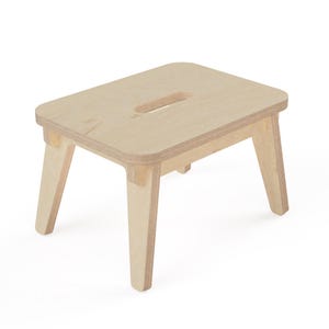 Puede incluir: Un taburete pequeño de madera clara fabricado en contrachapado con un acabado natural liso. El taburete presenta un asiento rectangular con esquinas redondeadas, un asa ovalada recortada en el centro y cuatro patas robustas ligeramente inclinadas.