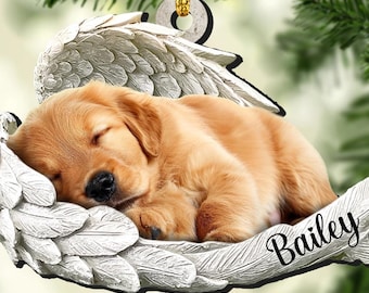 May include: A white ceramic angel wing ornament with a sleeping golden retriever puppy inside. The ornament has the name "Bailey" written on it.