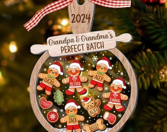 Może przedstawiać: Drewniana ozdoba choinkowa w kształcie piernikowego ludzika z przezroczystą plastikową kopułką. Ozdoba ma napis "2024 Grandpa & Grandma's Perfect Batch" na górze i imiona "Lucas, Oliver, Alex, Emma, Jack, Alice, Bailey" wewnątrz kopułki.
