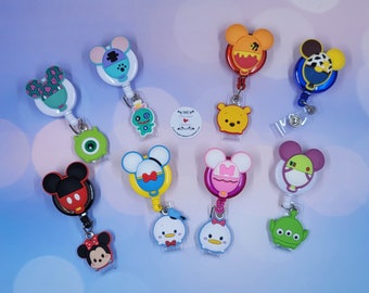 May include: A collection of ten retractable badge reels featuring various cartoon character designs, including Mickey, Minnie, Donald, Daisy, Winnie the Pooh, Mike Wazowski, and an alien. Each reel has a circular base and a dangling character charm.