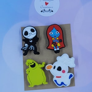 May include: A set of four colorful rubber shoe charms featuring characters from The Nightmare Before Christmas, including a skeleton, a red-haired figure, a green sack-like creature, and a white ghost dog, with a Thankful Creations logo sticker.