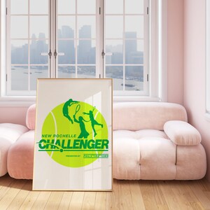 K&ouml;nnte beinhalten: Ein gerahmtes Poster mit einer gr&uuml;nen Tennisballgrafik und zwei Tennis spielenden Silhouetten. Der Text "New Rochelle Challenger" ist in gr&uuml;nen Buchstaben geschrieben, darunter die Worte "Presented by Phil's Tire Town".