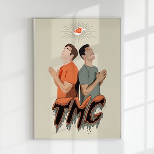 May include: Two men in orange and green shirts are praying with their hands clasped together. Above them is a red meat icon with a halo of light. The text "TMG" is written in black and orange dripping letters below them.