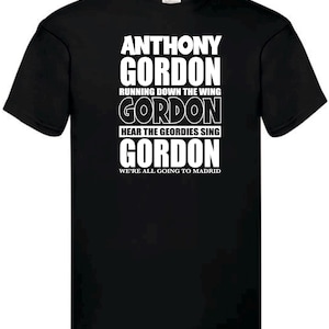 Może przedstawiać: Czarna koszulka z białym tekstem. Tekst brzmi "ANTHONY GORDON" na g&oacute;rze, a następnie "RUNNING DOWN THE WING", "GORDON", "HEAR THE GEORDIES SING", "GORDON" i "WE'RE ALL GOING TO MADRID" na dole.