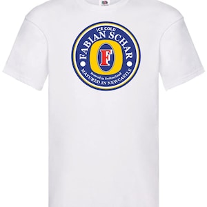 Puede incluir: Camiseta blanca con un logotipo azul y amarillo que dice "Ice Cold Fabian Schar Brewed in Switzerland Matured in Newcastle".