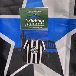 May include: Black and white striped football jersey fridge magnet with a blue star and the words "Town Toon's Black & White Army" in a circle. The magnet is packaged in a clear plastic bag with the words "The Back Page Football Souvenirs & Local Gifts" printed on it.