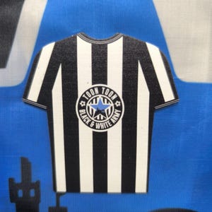 May include: Black and white striped soccer jersey with a circular patch that says "Toon Toon Black & White Army" with a blue star in the center.