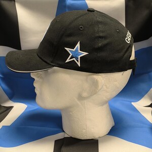 May include: A black baseball cap with a white brim and a blue star on the front. The cap has the word "GEORGIA" embroidered on the back.