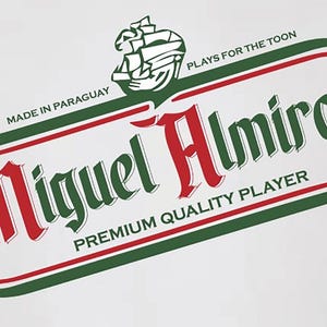 May include: A white t-shirt with a green and red logo that says "Miguel Almiron" with the text "Made in Paraguay" and "Plays for the Toon" above the logo and "Premium Quality Player" below the logo.