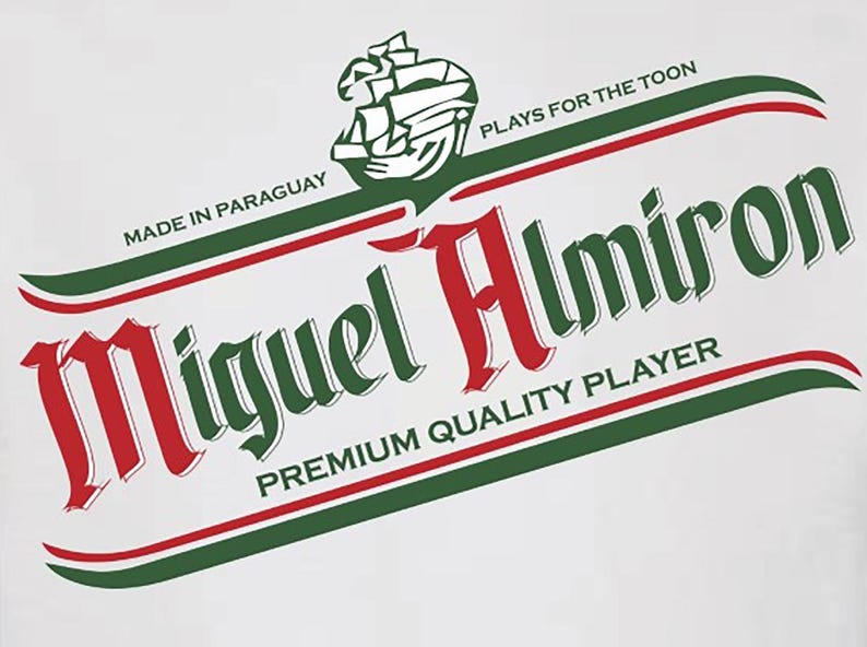May include: A white t-shirt with a green and red logo that says "Miguel Almiron" with the text "Made in Paraguay" and "Plays for the Toon" above the logo and "Premium Quality Player" below the logo.