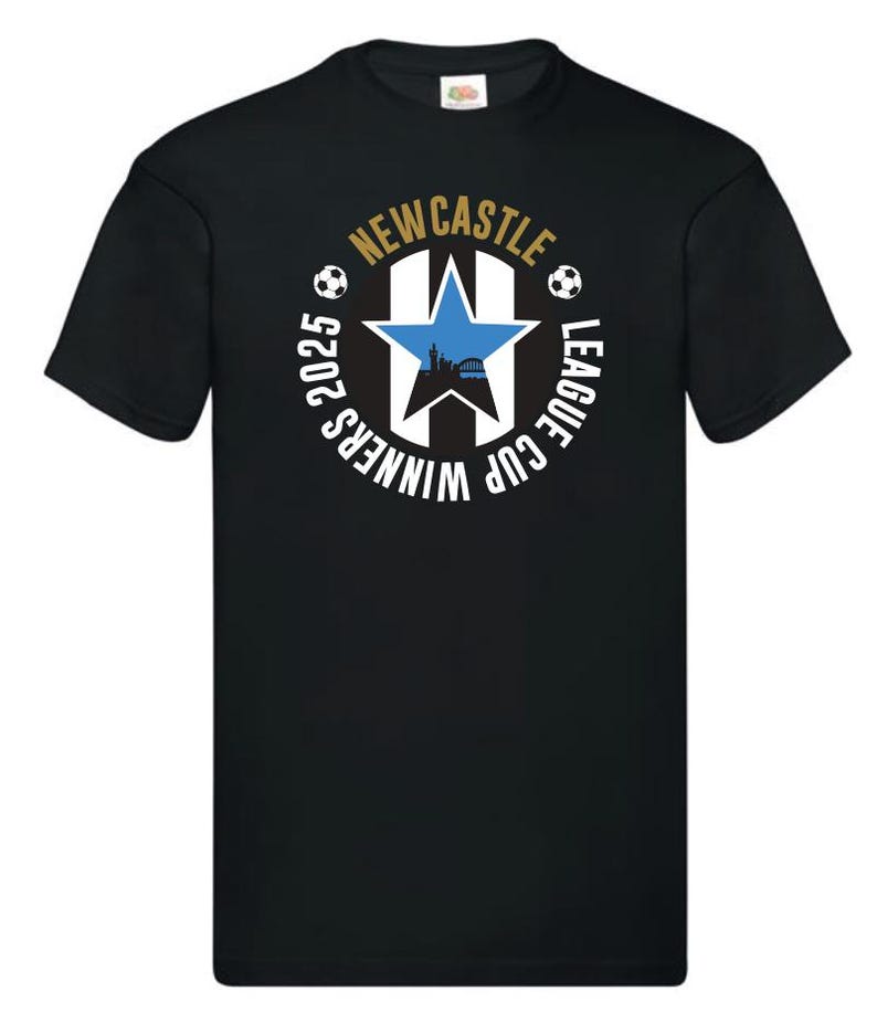 May include: Black t-shirt with a circular design. The design includes a blue star, a cityscape silhouette, and soccer balls. The text reads "NEWCASTLE LEAGUE CUP WINNERS 2025" in gold and white.