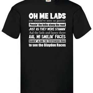 May include: Black t-shirt with white text. The text reads "OH ME LADS" followed by several lines of text about the Blaydon Races. The shirt has a crew neck and short sleeves. The shirt is made of a soft material.