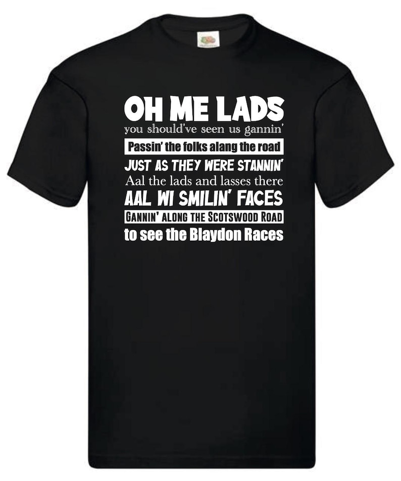 May include: Black t-shirt with white text. The text reads "OH ME LADS" followed by several lines of text about the Blaydon Races. The shirt has a crew neck and short sleeves. The shirt is made of a soft material.