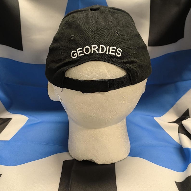 May include: Black baseball cap with a white embroidered logo that says "GEORDIES" on the back.