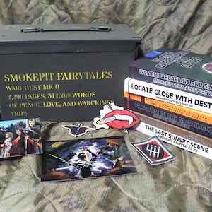 May include: An olive green metal ammo box with the text "SMOKEPIT FAIRYTALES" and book titles. Several books are stacked, with titles like "Women Barbarians and Slaves." Also included are art prints and stickers.