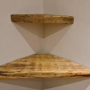 Pair of reclaimed scaffold board corner shelves, rustic industrial floating triangles for plants in a farmhouse-style corner.