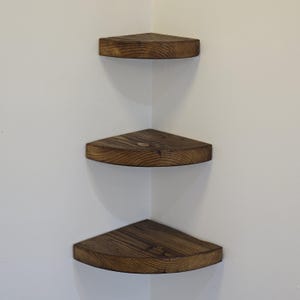 Reclaimed wood corner shelf set: three rustic round-corner scaffold-board shelves in a corner, ideal for plants.