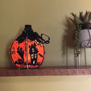 Lighted Haunted House Pumpkin with 3 different scenes - approx. 8.5 inches tall.  Shelf sold separate.