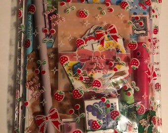 May include: A clear plastic bag filled with stationery items. The bag is decorated with red strawberries and bows. Inside are pens, stickers, and cards with text that reads "Just for you". The items are in various colors.