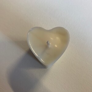 May include: A white heart-shaped candle with a single wick in the center.
