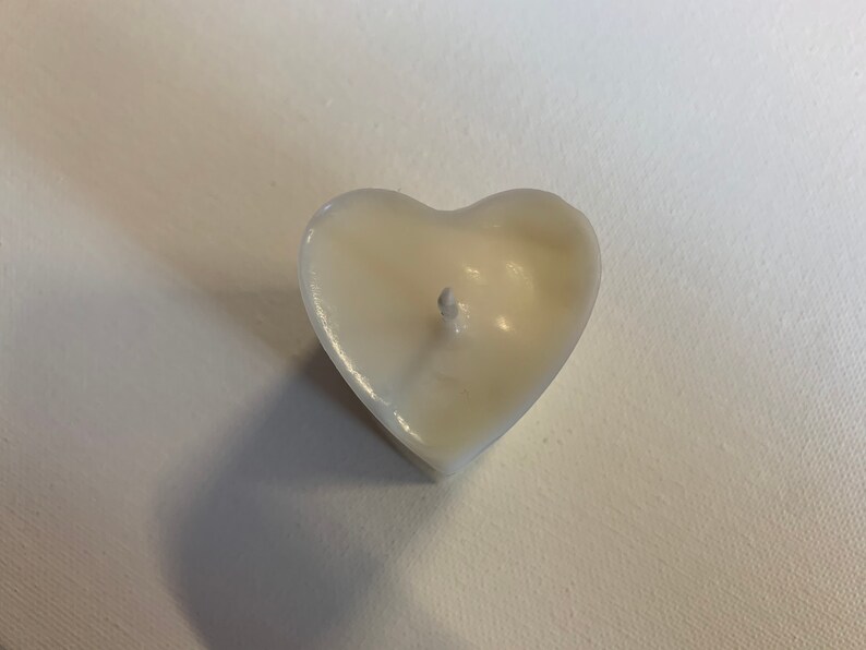 May include: A white heart-shaped candle with a single wick in the center.