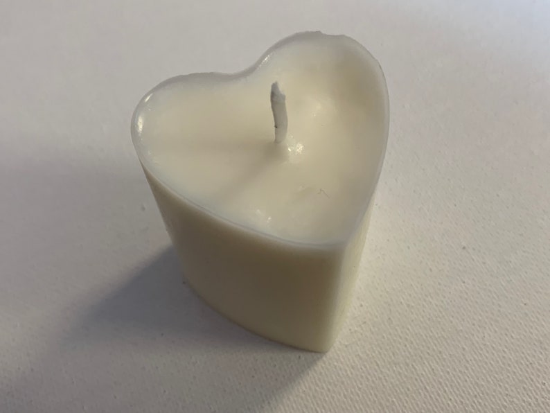 May include: A white heart-shaped candle with a single wick.
