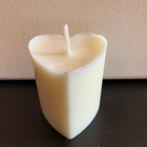 May include: A white heart-shaped candle with a single wick.