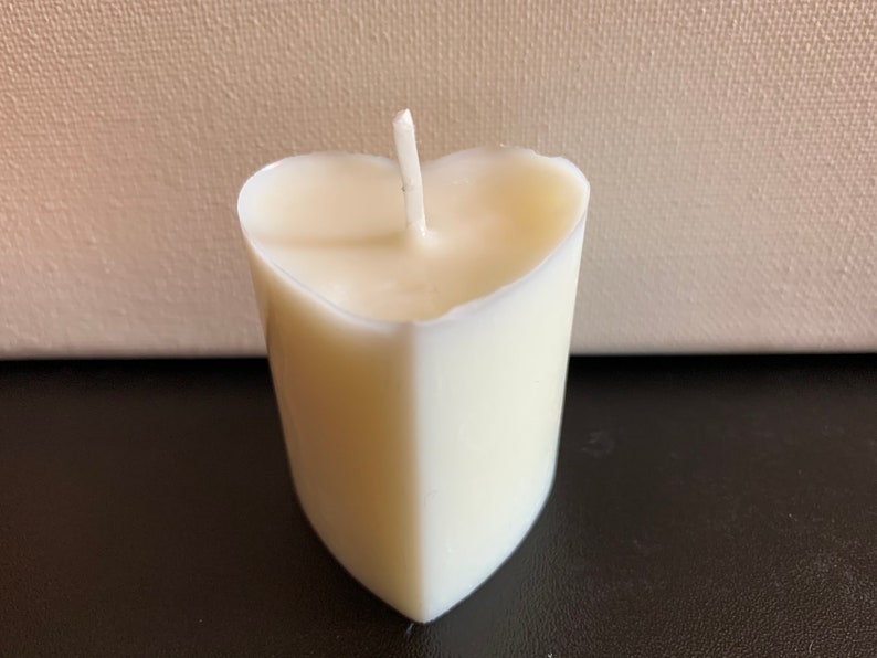 May include: A white heart-shaped candle with a single wick.