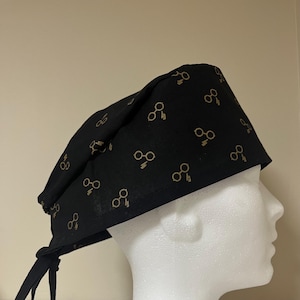 May include: Black scrub hat with a gold lightning bolt and glasses pattern.