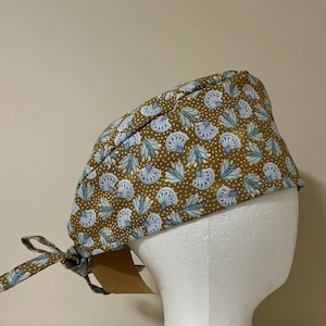 Peut inclure: Un bonnet de travail marron avec un motif floral bleu et blanc. Le bonnet a une attache à l'arrière.